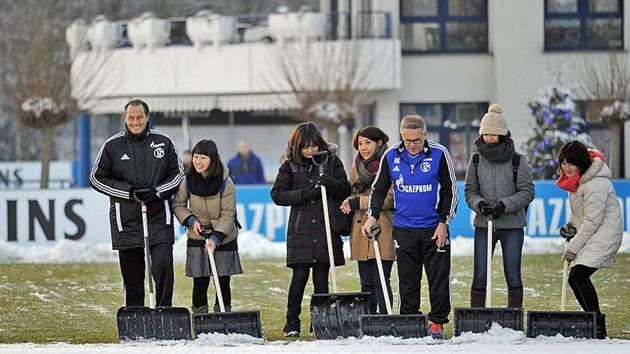 Huub Stevens, a Schalke edzője japán drukkerlányokkal takarítja a havat az edzőpályáról (forrás: bild.de)
