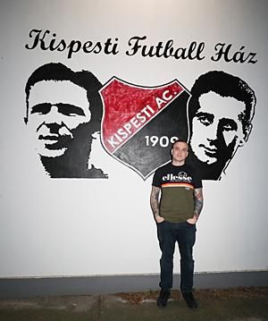 Kimmel Zsolt a Kispesti Futball Ház előtt, 
amelynek falán a Puskás Ferenc- és Bozsik József-portré
 az ő keze munkáját is dicséri (Fotó: Tumbász Hédi)