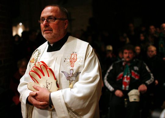 Heinrich Plochg katolikus plébános az Enkétől kapott kapuskesztyűkkel (Fotó: Reuters)
