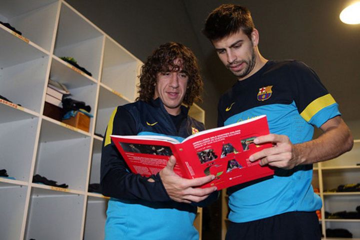 Puyol és Piqué egymás kezéből kapja ki a könyvet (Forrás: mundodeportivo.com)