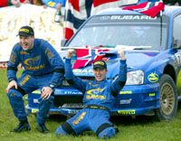 Petter Solberg felszabadultan ünnepelte az egész éves tekerést navigátora, Phil Mills (balra) és a világverô Subaru társaságában