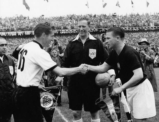 Csapatkapitányok kézfogása a berni Wankdorf Stadionban 1954. július 4-én, 17 órakor, az NSZK–Magyarország világbajnoki döntő előtt. Balra a nyugatnémet Fritz Walter, jobbra Puskás Ferenc, középen a labdát fogó angol játékvezető, William Ling