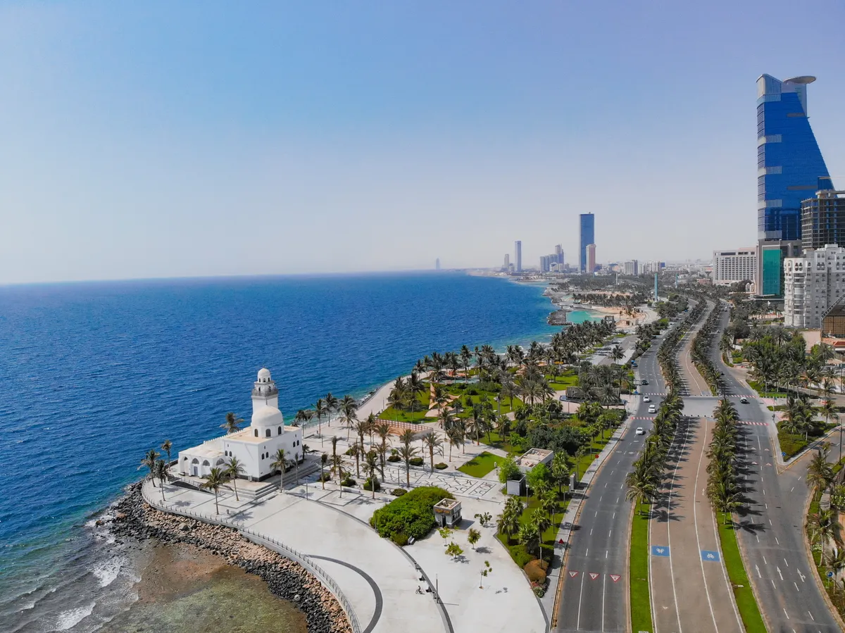An  aerial  view  of  a  beautiful  seaside  park  with  palms  and  cityscape  in  the  Saudi  Arab